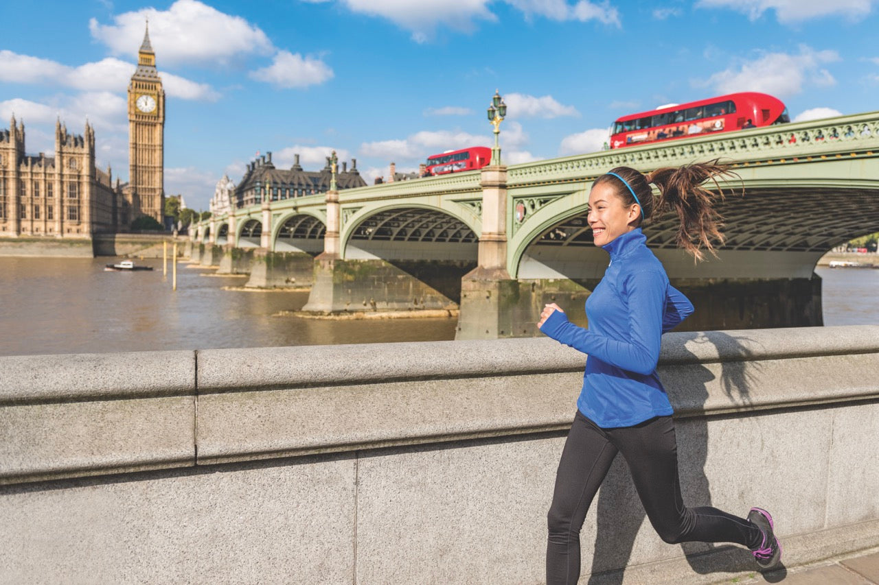 Woman jogging near Big Ben and the River Thames, staying active and hydrated.